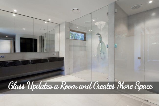 A long sink to the left with a mirror and to the right a frameless glass shower