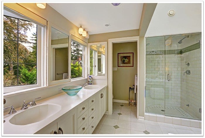 Bathroom with two sinks and a frameless glass shower in the corner