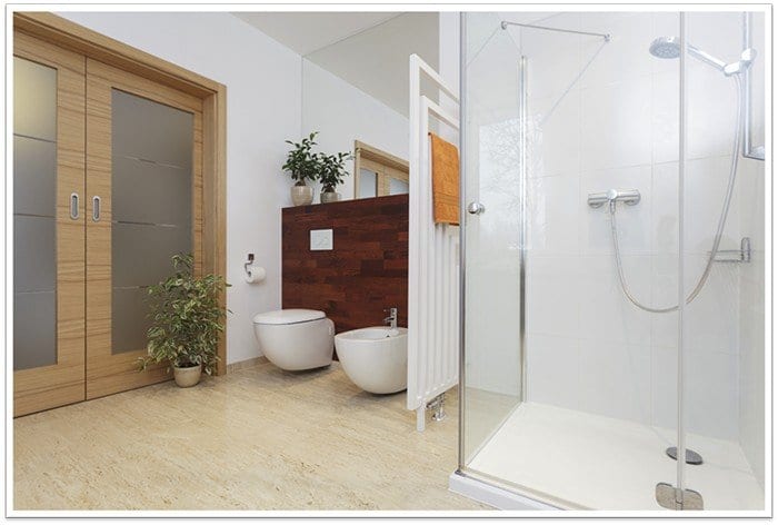 two toilets to the left of photo and a frameless glass shower to the right