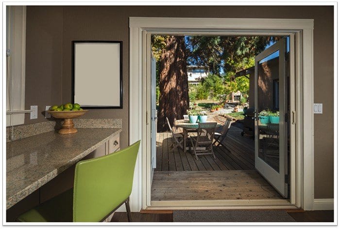 a green chair to the left with a walkway in the center leading outside to a yard