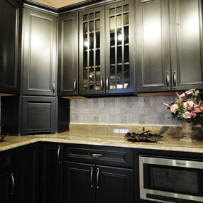 If you have to work with your existing cabinets, you can bring them more in line with old styles by replacing some of the wooden door fronts with cabinet glass.