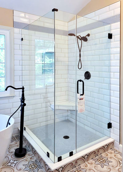 Often the bathtub or shower stall is hidden behind a shower curtain, making both the room and the stall feel quite compact. Try replacing the curtain with an enclosure.